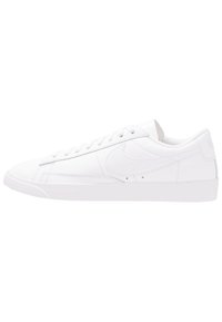 White leather sneaker with flat laces, rounded toe, textured side panel, and logo on the heel. Features a rubber sole and minimalist design.
