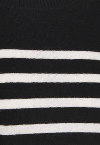 Musta-valkoraidallinen neulepusero, jossa vaakasuorat raidat, teksturoitu kangas, resorireunus kaula-aukossa ja pehmeä, neulottu viimeistely.