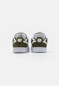 Grønne semskede sneakers med hvide og grå accenter, teksturerede gummisåler og et gult logo på hælkappen.