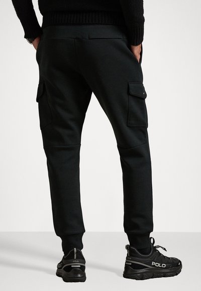 Svarta cargojoggers med sidofickor, ribbad mudd och en slät tygfinish. Bärs med svarta sportskor i låg profil.