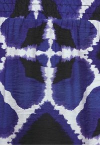 Kangas, jossa on rohkea, abstrakti kuvio violetein, mustin ja valkoisin sävyin. Kangas on ryppyinen ja sen yläosassa on kerätty joustava osa.