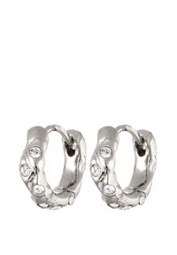 Boucles d'oreilles en argent en forme de cerceau avec un design ondulé, présentant quatre petites pierres transparentes incrustées sur chaque boucle.