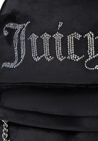 Črn nahrbtnik iz mehkega materiala, na katerem je napis "Juicy" v srebrnih rhinestones. Vsebuje podrobnosti iz verige na dnu.
