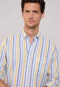 Camisa de botones con rayas verticales en amarillo, azul y blanco. Fabricada en una tela ligera con un bolsillo en el pecho y mangas con puños.