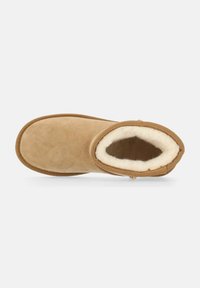 Tan-farbenes Wildleder-Ankle-Boot mit weicher, cremiger Schaffellfütterung und abgerundeter Zehenpartie. Verfügt über ein einfaches Stichdesign entlang der Ränder und eine glatte Textur.