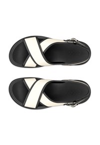 Black and white sandals with a cross-strap design. Made of synthetic upper material and rubber sole. Includes a decorative buckle detail.