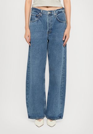 Jean large bleu clair en denim, comportant cinq poches, une fermeture à bouton et une finition légèrement délavée.