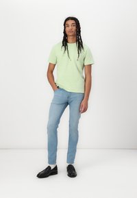 Lys grøn bomulds t-shirt, slim-fit lyseblå jeans og sorte loafers, med en glat tekstur og minimale designelementer.