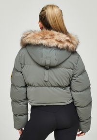 Olijfgroene gewatteerde jas met een faux fur capuchon, met een cropped ontwerp, pofy mouwen en een gespdetail op de rug.