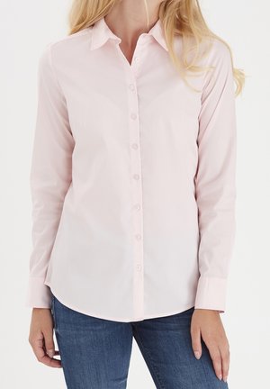 Chemise boutonnée rose clair avec un col classique, des manches longues et un ourlet arrondi. Fabriquée en tissu lisse avec un léger éclat.