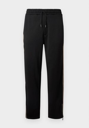 Pantalon de sport noir avec taille élastique, cordon de serrage, bandes latérales et fermetures éclair aux chevilles, présenté sur un fond blanc.
