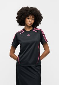 Μαύρο αθλητικό μπλουζάκι με ροζ λεπτομέρειες και τρεις ρίγες στους ώμους. Διαθέτει στρογγυλή λαιμόκοψη και ομαλή υφή.