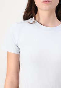 Ανοιχτό μπλε βαμβακερό μπλουζάκι με στρογγυλή λαιμόκοψη και κοντά μανίκια. Λείος υφασμάτινος ιστός με ελάχιστη ραφή στα μανίκια.