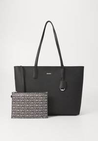 Mustat nahkakärryt, joissa on kaksi kahvaa ja hopeinen DKNY-logo. Mukana on pienempi pussi, jossa on toistuva logokuvio harmaana.