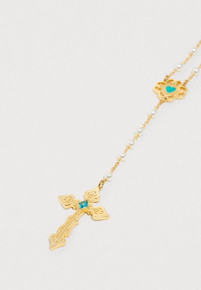 Pandantiv în formă de cruce aurie cu detalii elaborate, având o piatră turcoaz în centru. Este prins de un lanț din perle și aur, decorat cu o inimă.