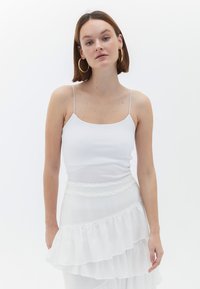 Witte geribde tanktop met dunne bandjes, gecombineerd met een gelaagde witte rok met ruches, gemaakt van een gestructureerde stof en met een ruches tailleband.