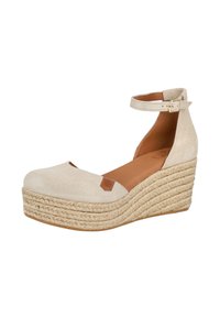 Zapato de cuña de ante beige con punta redonda, correa al tobillo y plataforma envuelta en yute. Presenta un parche de acento marrón en el costado.