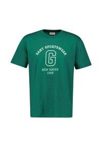 Camiseta de algodón verde con mangas cortas, que presenta "GANT SPORTSWEAR," una gran 'G', "NEW HAVEN 1949" en impresión blanca en la parte frontal.