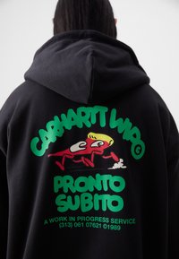 Black hoodie featuring a large graphic print on the back. Design includes green text and a whimsical cartoon figure in red and yellow.