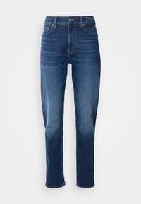 Temno modri kavbojki s ravnim krojem, ki imajo visok pas, pet žepov in kovinske dodatke na gumbu ter nitnih spojih.