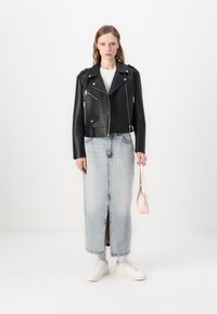 Svart faux skinn bikerjakke med sølvglidelåser, hvit t-skjorte, lyseblå denimskjørt og hvite sneakers. Holder en rosa veske.