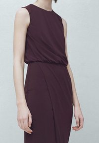 Burgundowa sukienka bez rękawów z marszczoną talią, gładką fakturą i eleganckim, drapowanym krojem, charakteryzująca się prostą, minimalistyczną sylwetką.