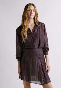 Vestito nero trasparente con strisce verticali multicolori, collo a camicia, maniche arricciate e orlo asimmetrico con design a incrocio.