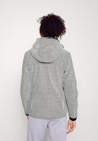 Grau gemusterte Outdoor-Jacke mit Kapuze, ausgestattet mit Reißverschlusstaschen und elastischen Bündchen. Von hinten vor einem schlichten Hintergrund dargestellt.