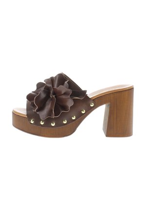 Brown leather heeled sandal with a large ruffled flower detail, gold studs along the side, and a wooden block heel.