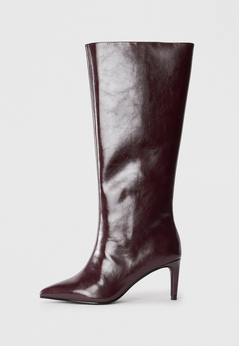 Botte en cuir bordeaux foncé, haute et élancée, avec un bout pointu et un petit talon mince. Surface lisse et brillante, isolée sur fond blanc.
