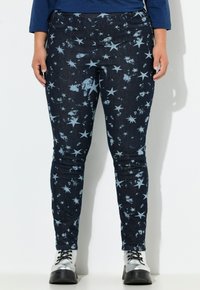 Skinny jeans in donkerdenim met een sterrenpatroon in lichtblauw. Voorzien van vijf zakken en een knoopsluiting. Afgewerkt met een subtiele distressed textuur.