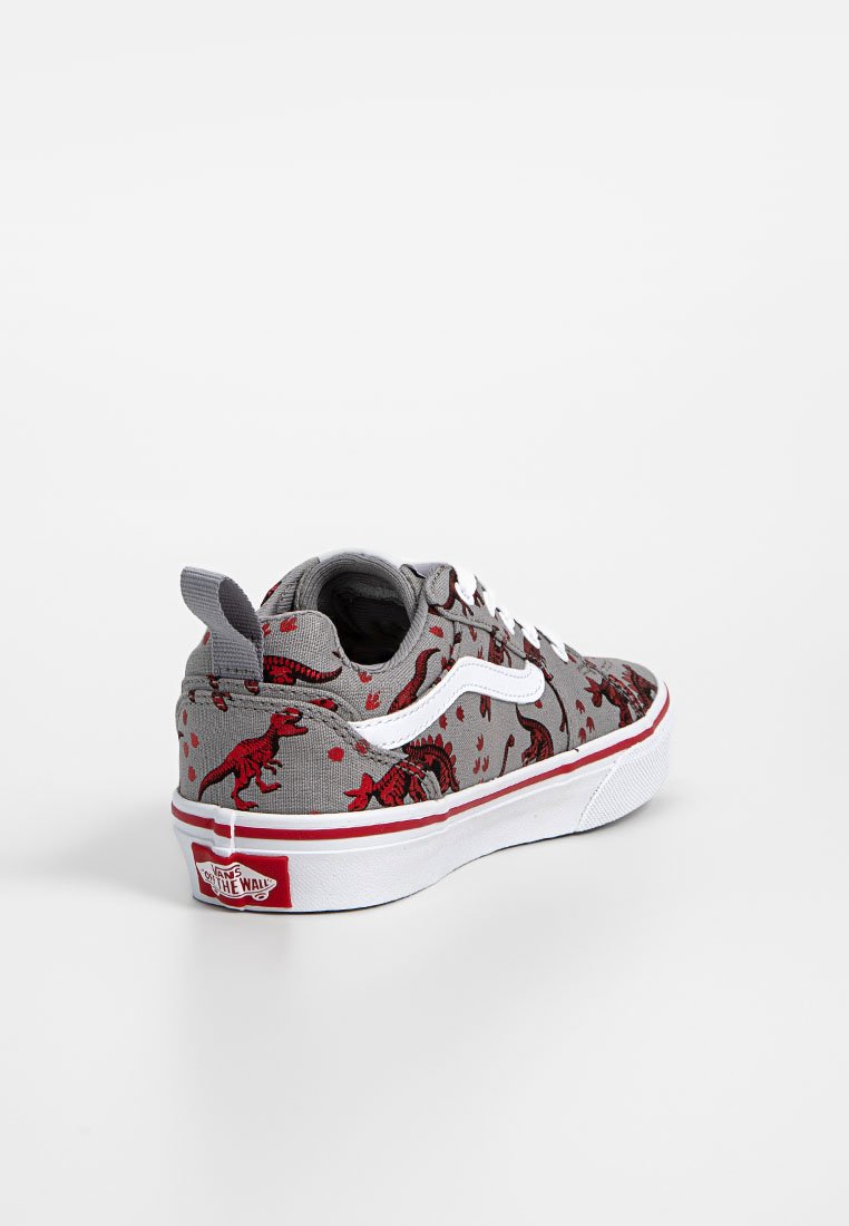 Zapatilla de lona gris con patrones de dinosaurios rojos, cordones blancos y suela de goma blanca. Presenta el logo de Vans en el talón y una solapa.