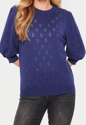Pull en maille bleu marine avec des manches bouffantes, comportant un design à œillets décoratifs, des poignets côtelés et un col rond.