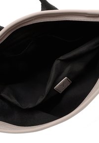 Světlé růžová taška přes rameno s černým vnitřkem, vyrobená z odolné látky. Má dvě rukojeti a malou označenou štítek uvnitř.