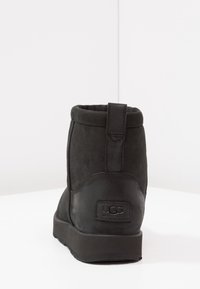 Czarne zamszowe botki za kostkę z okrągłym noskiem, wyściełanym kołnierzem i oznakowaną naszywką na obcasie. Posiadają krótką tylną pętlę ułatwiającą zakładanie.