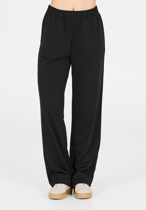 Pantalons noirs amples avec une taille élastique, fabriqués en tissu doux ; coupe droite avec une texture subtile et un minimum de détails de design.
