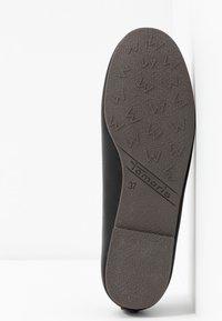 Svart sko med en texturerad gummisula som har ett zigzag-mönster. Varumärket är präglat på sidan. Storlek 37 angiven.