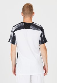 Herre atletisk t-shirt med hvidt krop og kortærmer samt ryg i sort-hvid mønster. Fremstillet af letvægtsstof med rund halsudskæring.