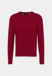 Maglione rosso realizzato in morbido tessuto a maglia, con scollatura a girocollo, maniche lunghe e un piccolo logo ricamato sul petto.