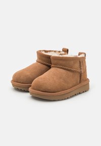 Braune Wildleder-Ankle Boots mit weichem Fellfutter, einer runden Zehenform und einer strukturierten Gummisohle. Verfügt über einen gesteppten Akzent und einen Zugriemen an der Rückseite.