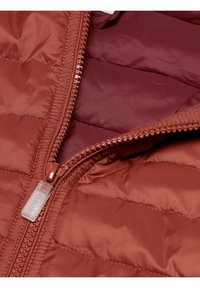 Červená zateplená bunda s prošívanou texturou, vpředu na zip a vnitřním podšívkou v tmavší červené barvě. Zip má jasně viditelnou táhlo.