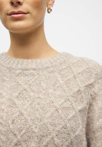 Suéter de punto beige con un patrón de diamantes texturizados, cuello redondo y puños acanalados de material suave y esponjoso.