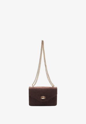 Rjava suede torbica s zlatim verižnim ročajem, pravokotne oblike, z zapiranjem na poklopcu in ovalnim kovinskim dodatkom spredaj.