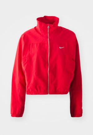 Veste rouge courte en tissu léger, dotée d'un col haut, d'une fermeture éclair, d'une taille élastique et d'un petit logo blanc sur la poitrine.