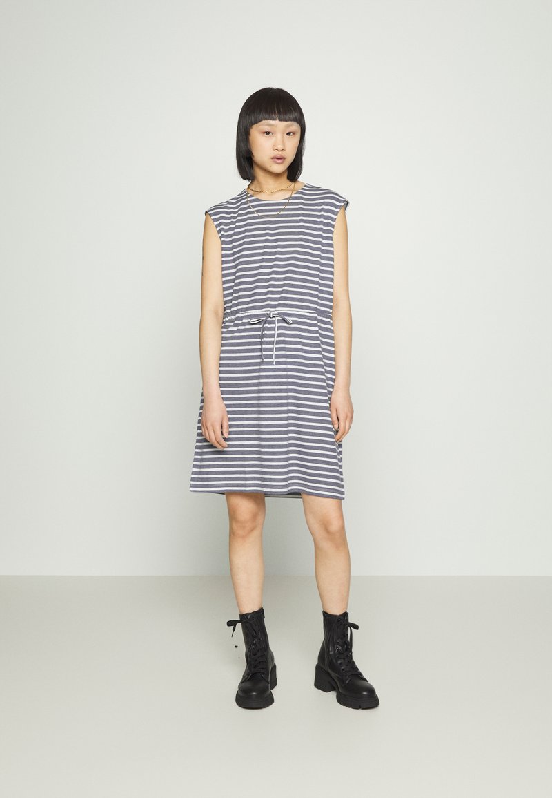 Vestido riscado em azul-marinho e branco, de mangas curtas, com cintura ajustada e cordão. Combinado com botas de combate pretas com atacadores.