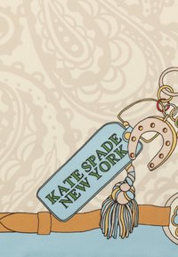 Mønstrede stoffer har beige paisley-designs. Et blåt mærke står der "KATE SPADE NEW YORK" med et hestesko og flerfarvede frynse-detaljer.