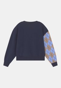 Námořnická modrá mikina s krátkým střihem. Jeden rukáv má světle modrý a hnědý kostkovaný vzor. Měkká textura a žebrovaný límec.