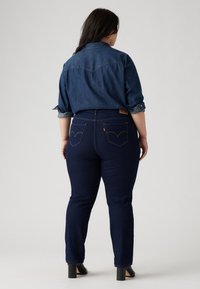 Denimskjorta med detaljer på ryggen, bärs över mörkblå jeans med smal passform, med signatur bakfickor och uppvikta ärmar.