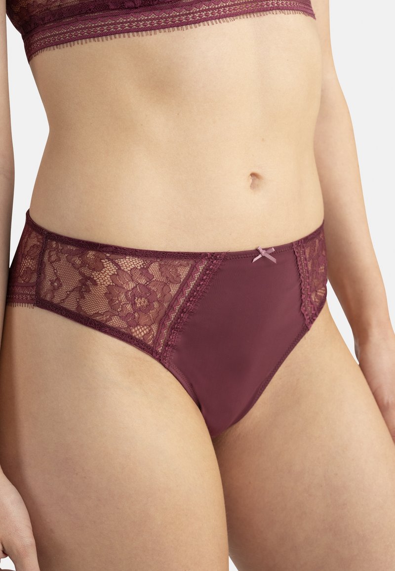 Culotte en dentelle bordeaux avec un motif floral, des accents en satin et un petit nœud à l'avant. Matériau lisse combiné à de la dentelle texturée.