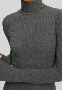 Maglione grigio a collo alto a coste, realizzato in un tessuto morbido, con un design aderente, maniche lunghe e una texture del colletto alta.